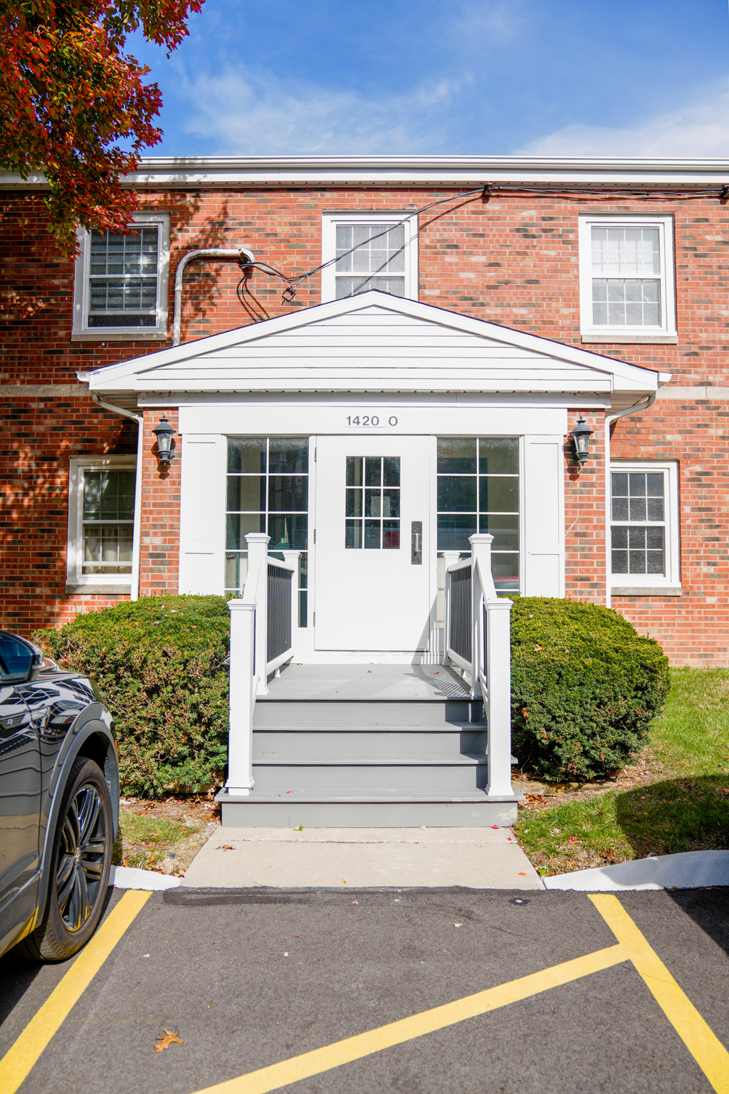 the front of a red brick building with white steps and a white door