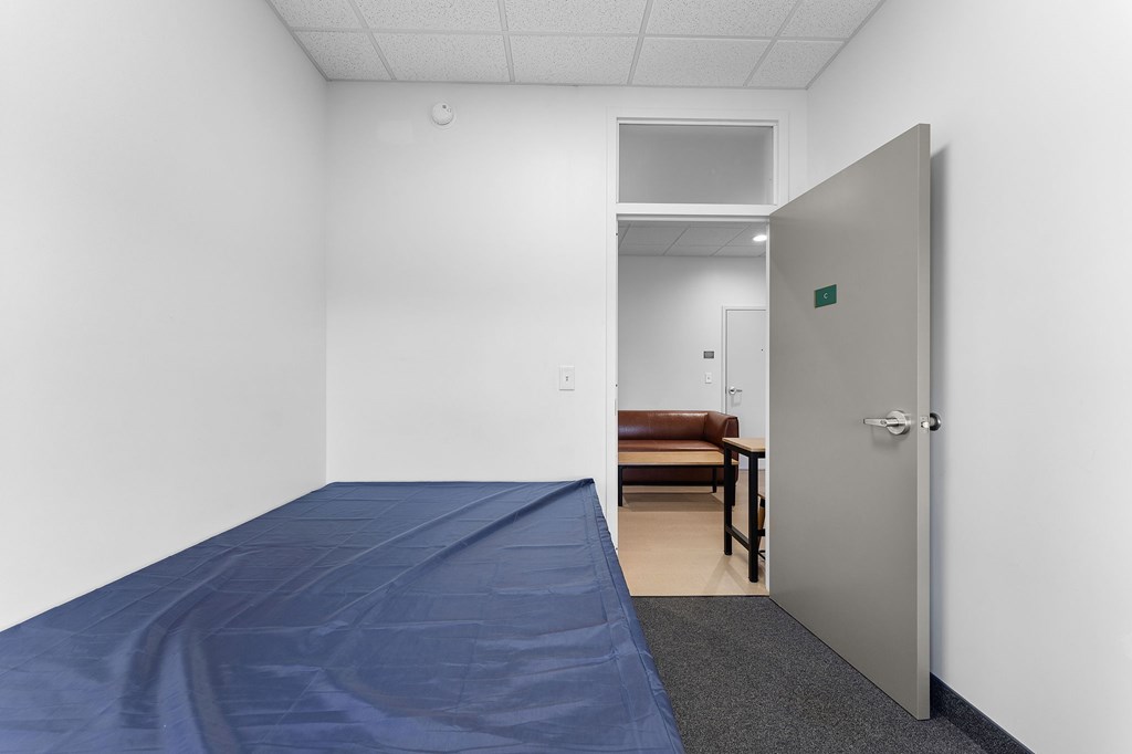 A room with a blue tarp on the floor and a door on the right.