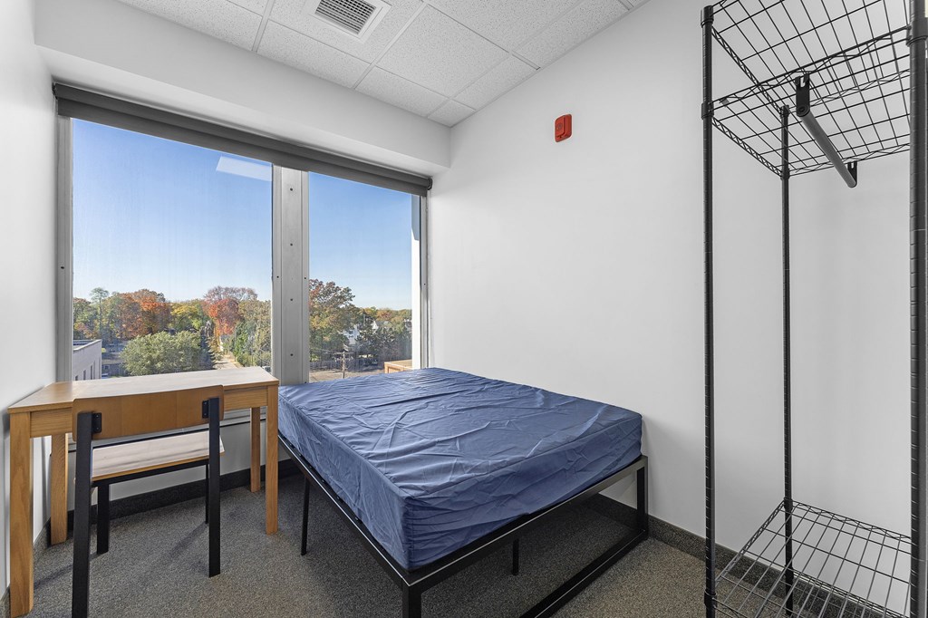 A bedroom with a bed, desk, and chair.