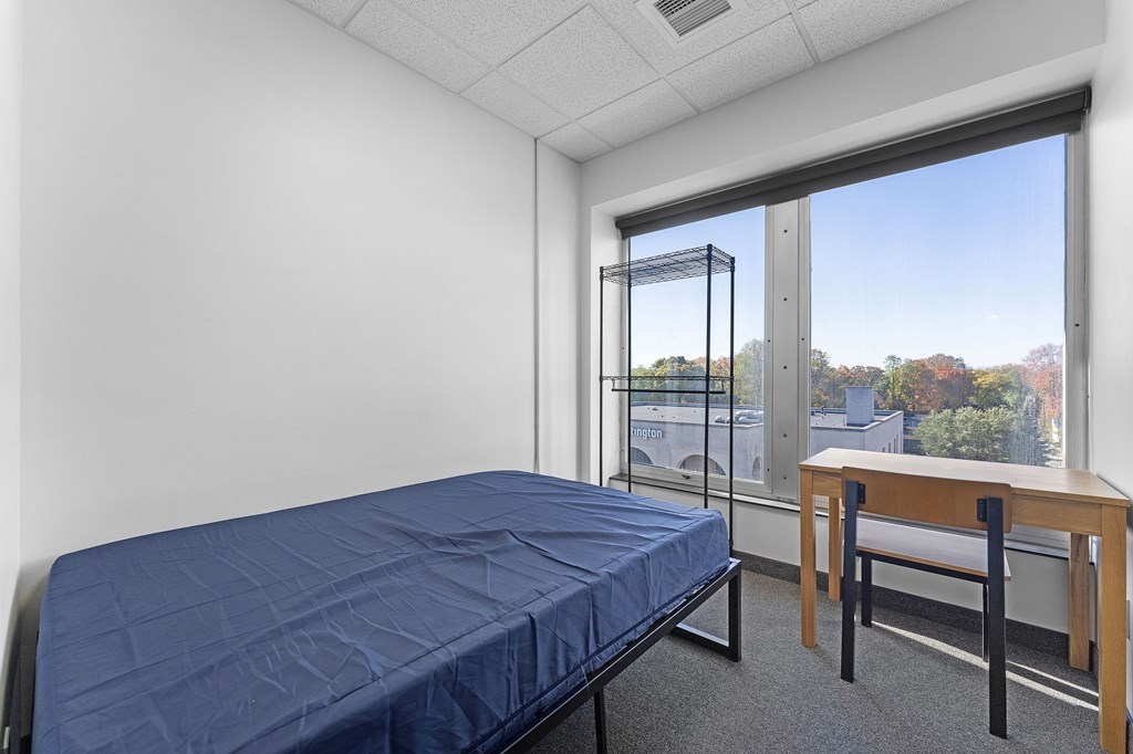 A bedroom with a bed, desk, and chair.