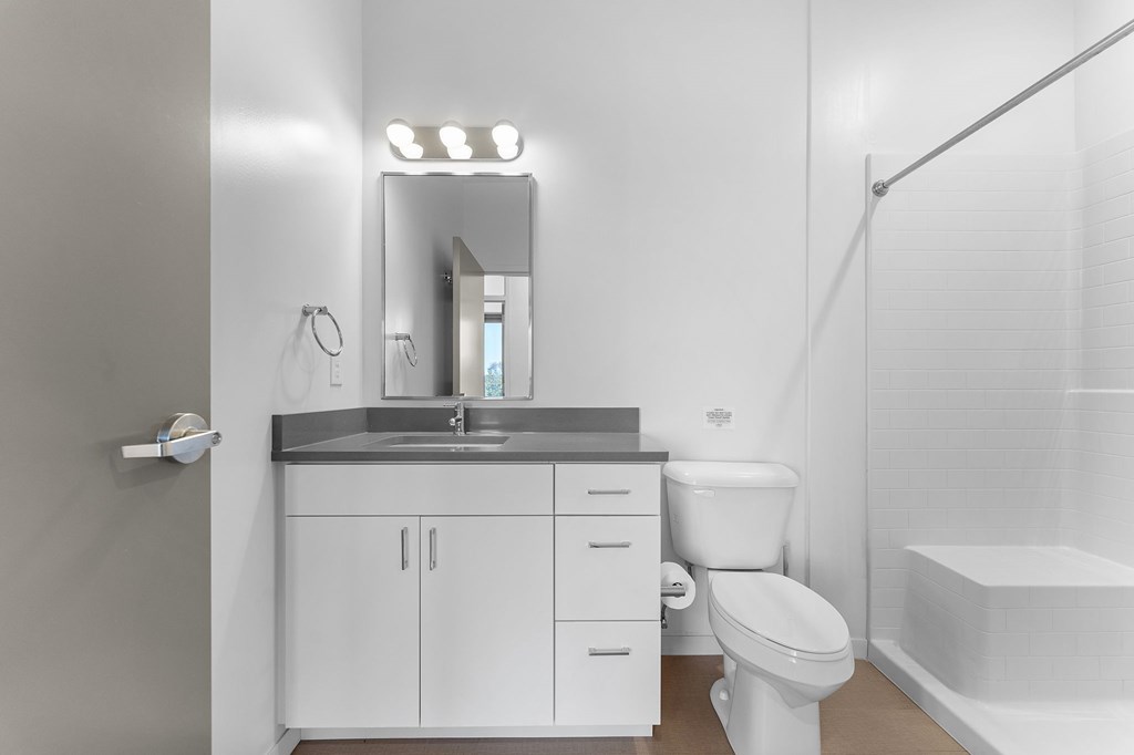 A white bathroom with a sink, toilet, and mirror.