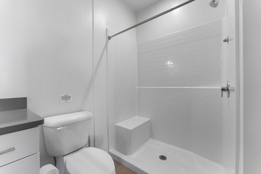 A white toilet sits next to a white bathtub in a bathroom.