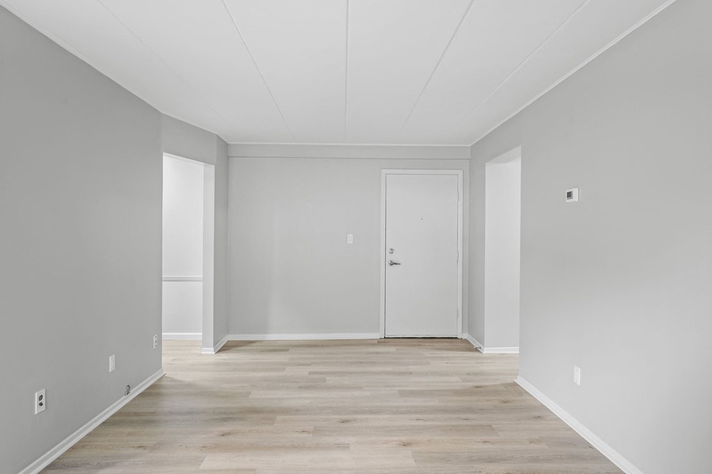 an empty room with white walls and wood floors