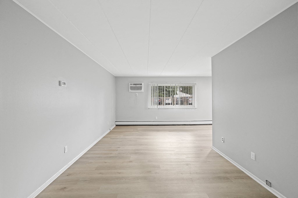 a spacious living room with white walls and a window