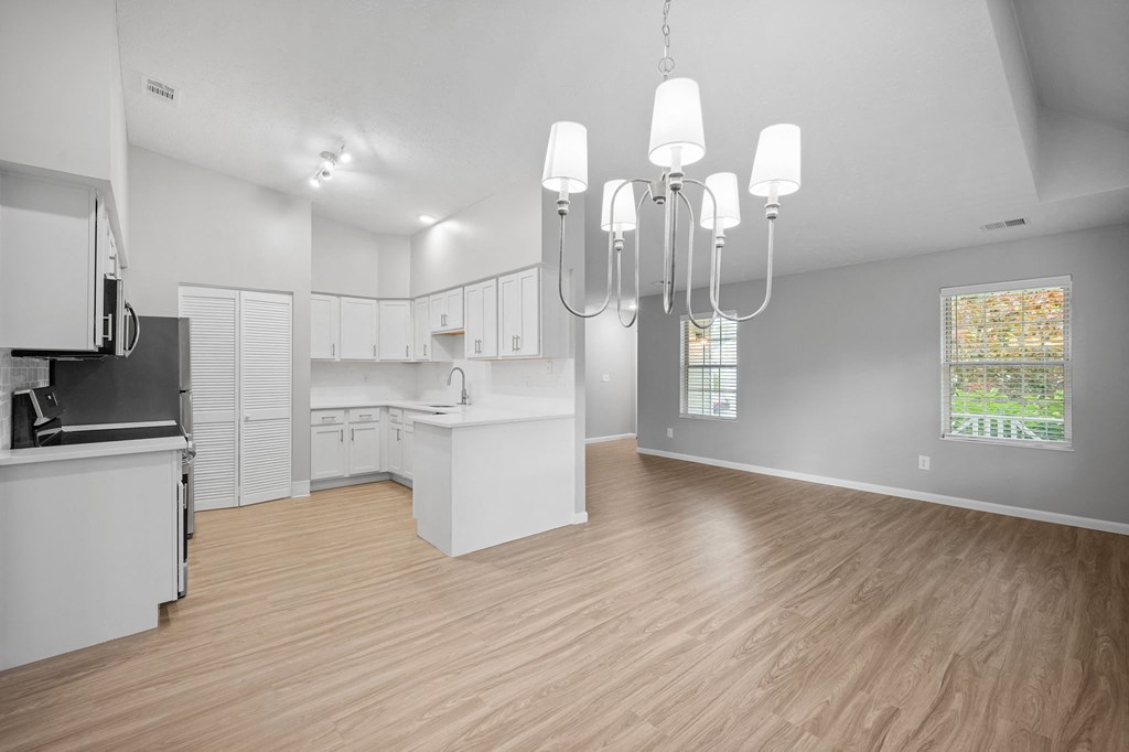 a living room with a kitchen and a chandelier
