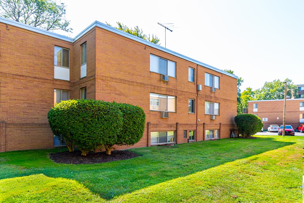 the exterior of an apartment building with a yard and green grass