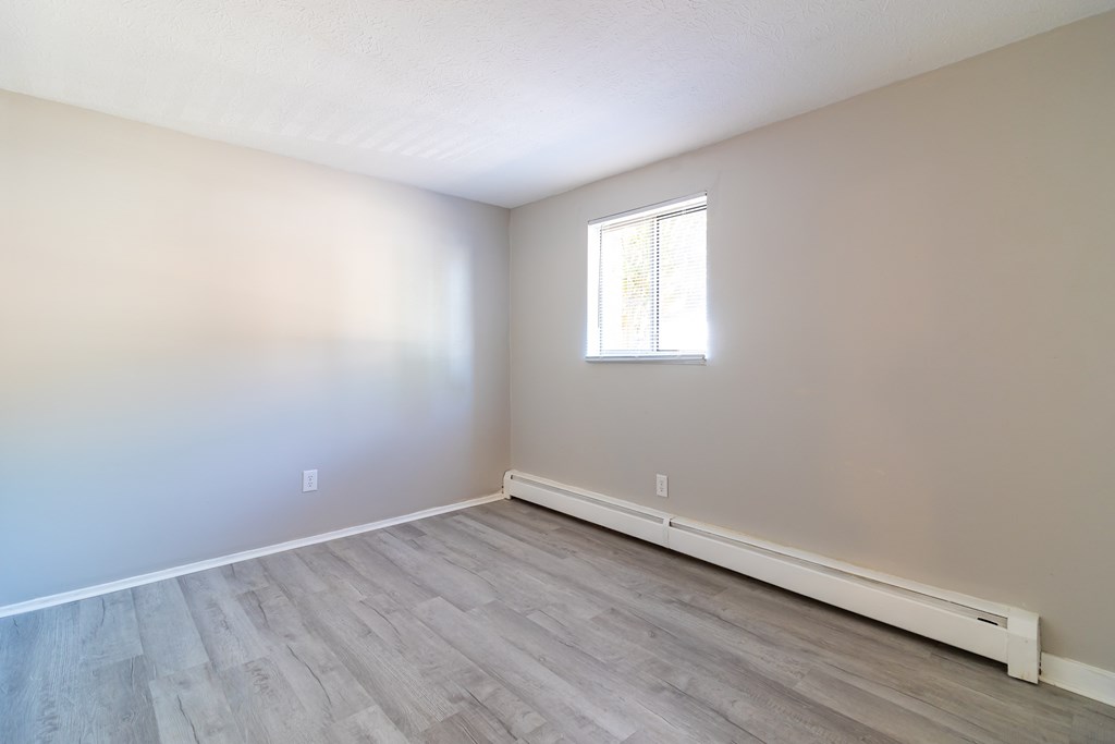 an empty room with wood flooring and a window