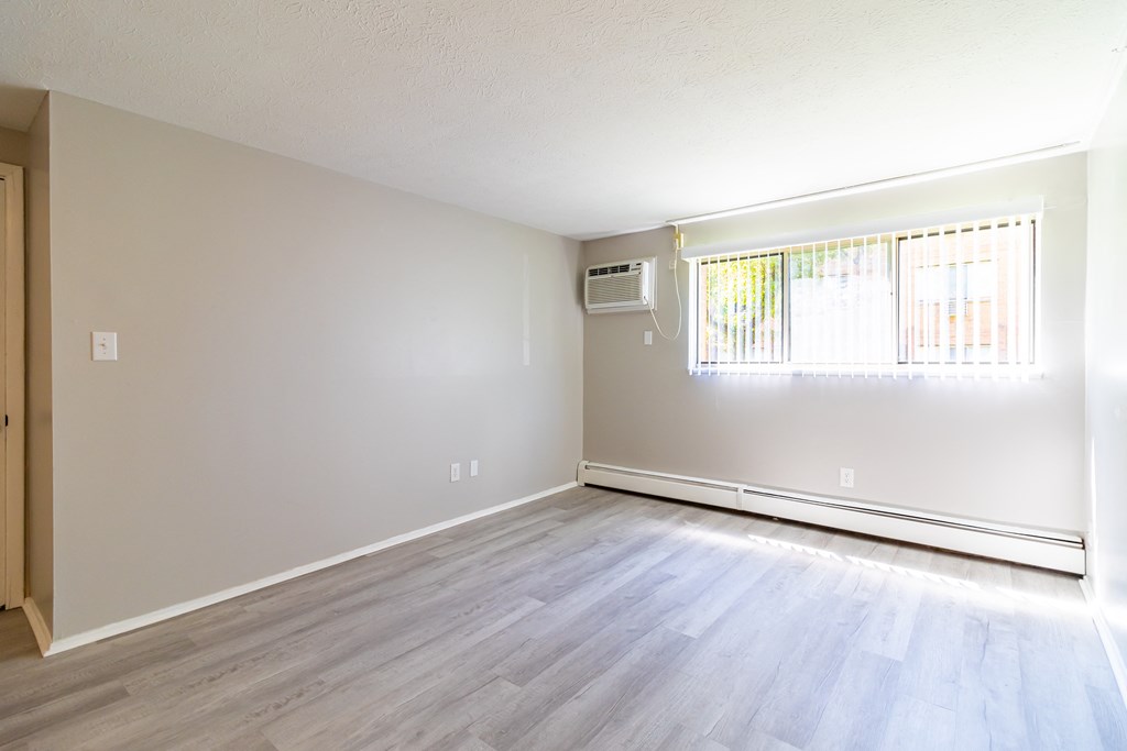 an empty living room with wood floors and a window