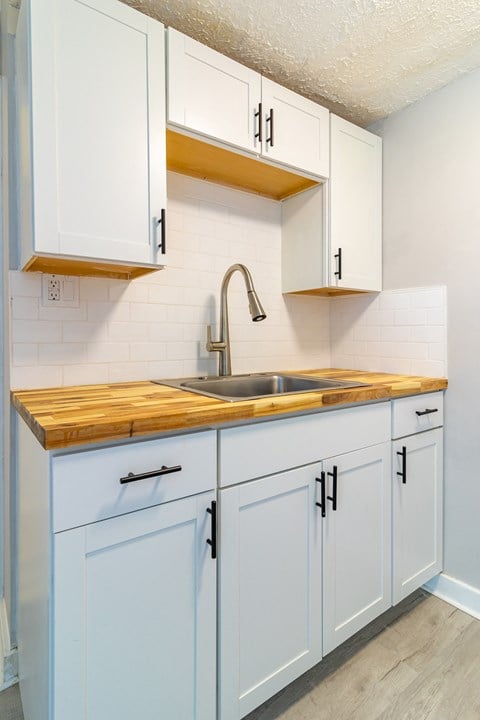 a kitchen with white cabinets and a sink and a wooden counter top