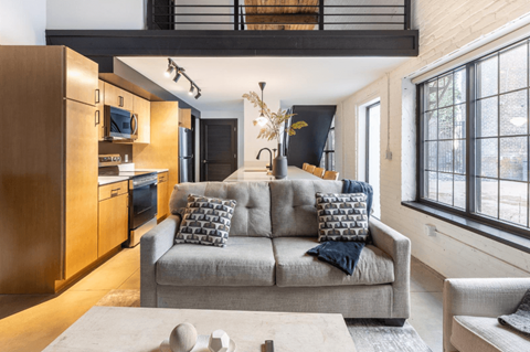 A modern living room with a grey couch and a wooden cabinet.