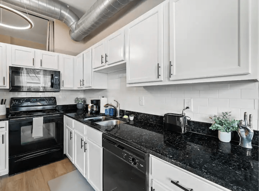 a kitchen with white cabinets and black counter tops