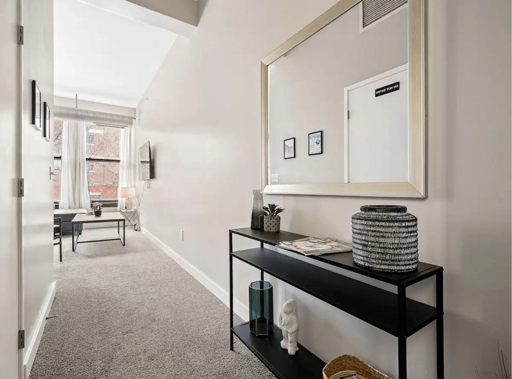 a hallway with a large mirror and a black shelf