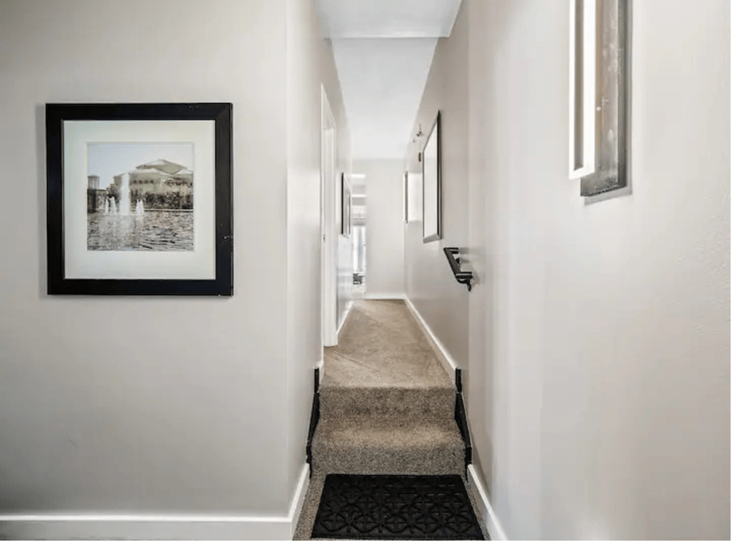 a long hallway with a picture hanging on the wall and a runner on the floor