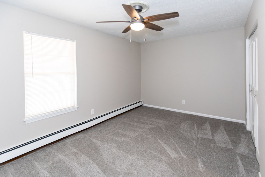 an empty room with a ceiling fan and a window