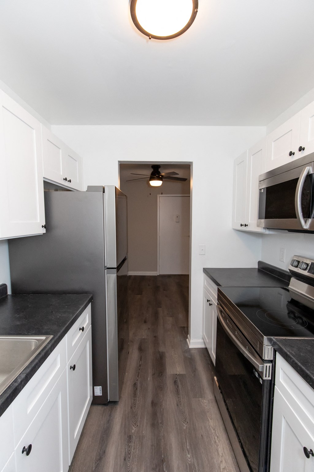 a kitchen with white cabinets and stainless steel appliances and a door to a hallway