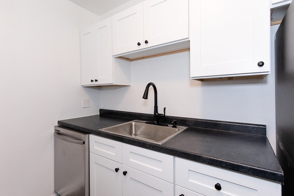 a kitchen with white cabinets and black counter top and a sink