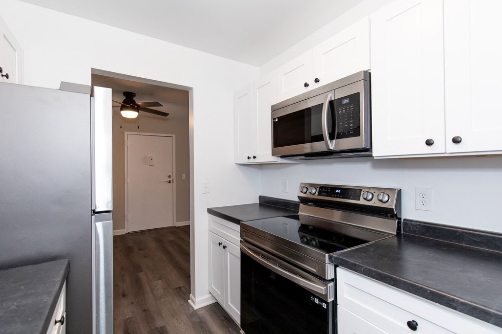 a kitchen with white cabinets and black counter tops and stainless steel appliances