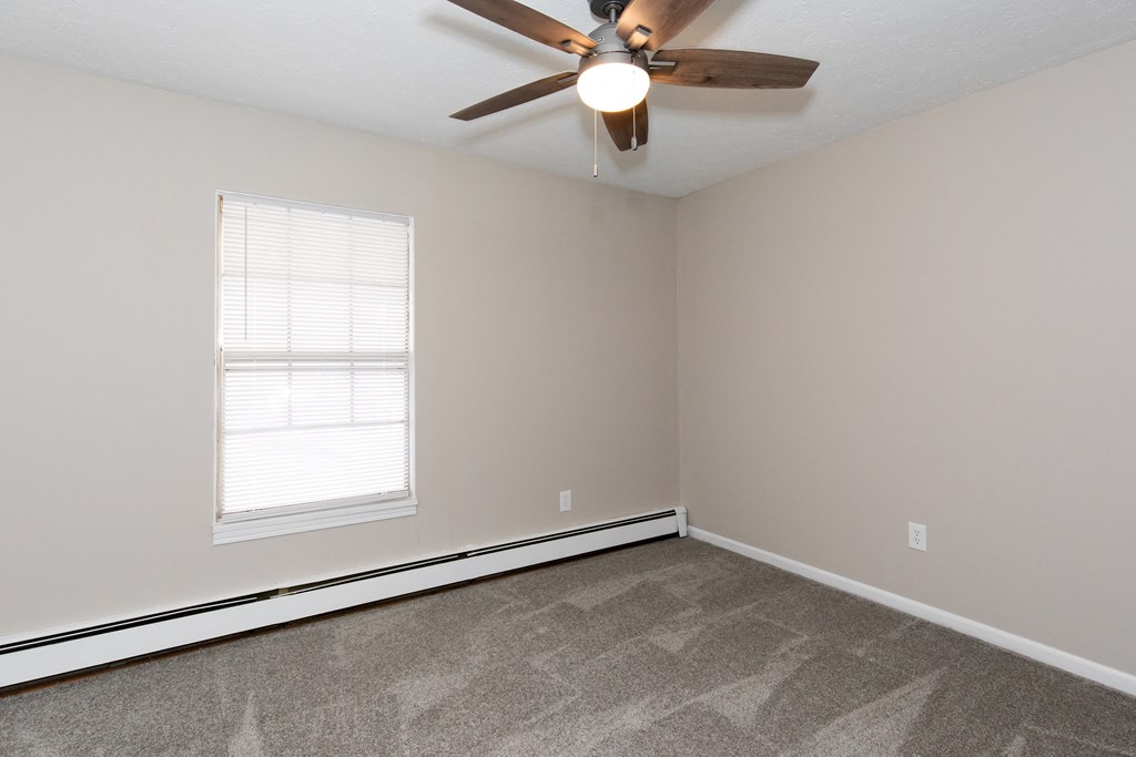 an empty living room with a ceiling fan and a window
