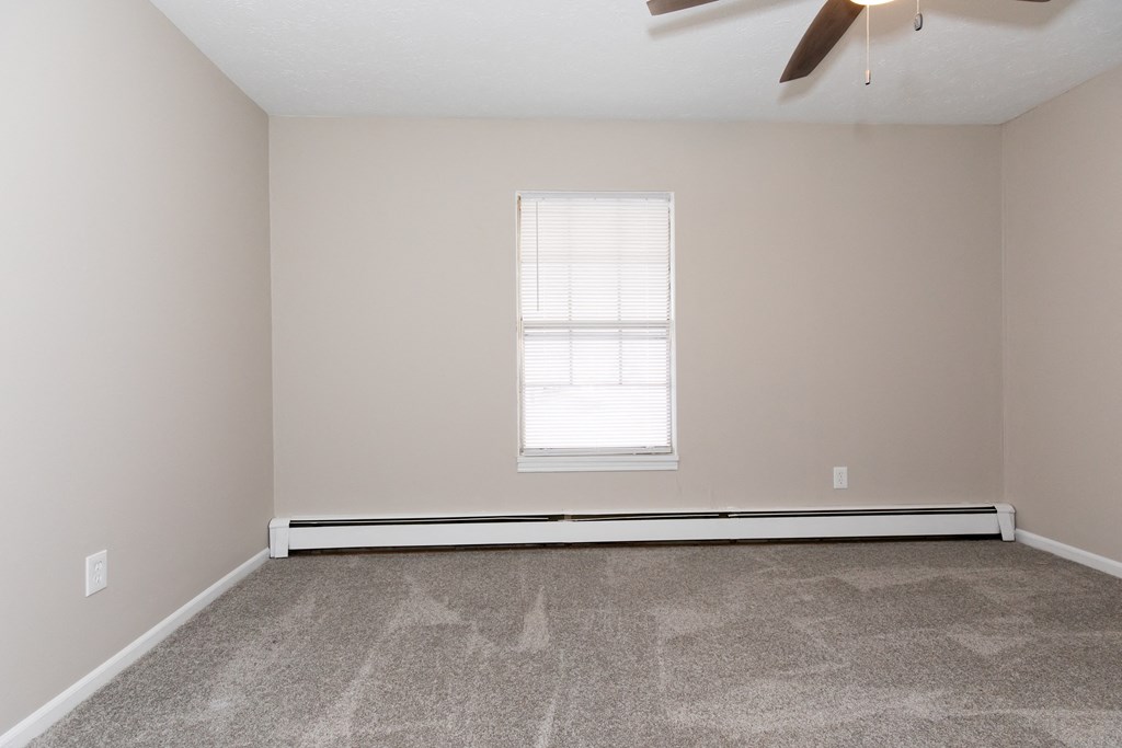 an empty room with a window and a ceiling fan