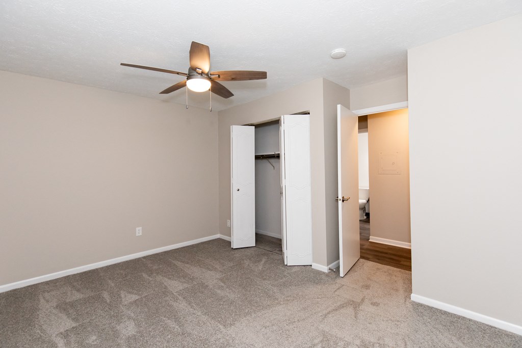 an empty living room with a ceiling fan and a closet