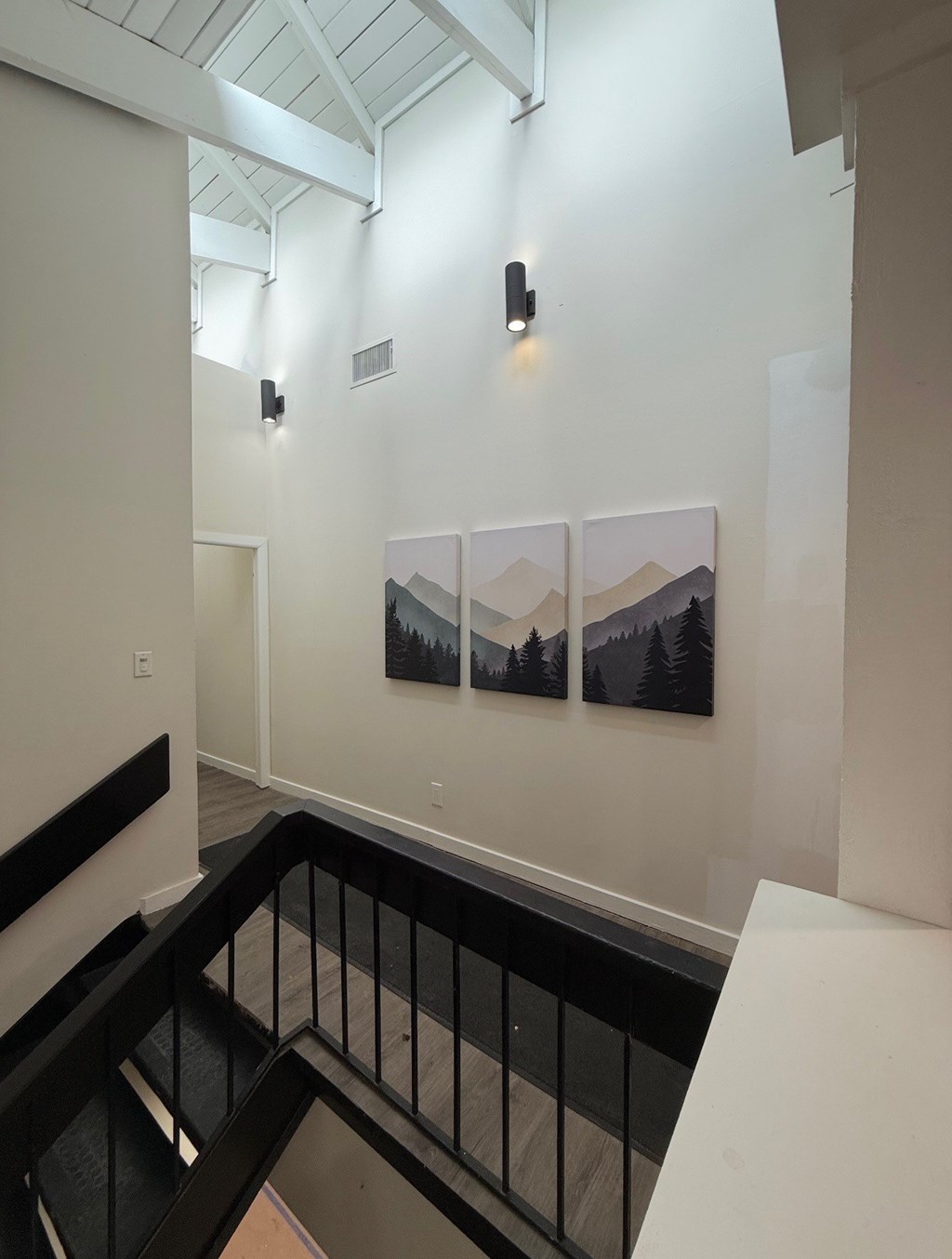 A hallway with a black railing and three pictures on the wall. at Commons At Waters Edge, Columbus Ohio