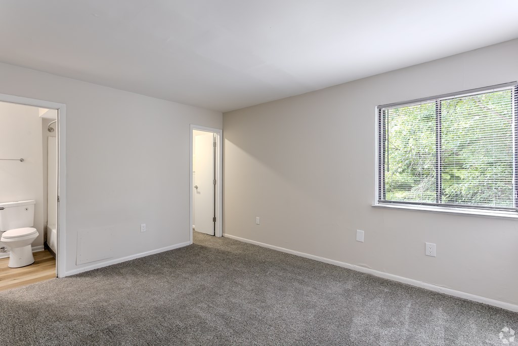 A spacious room with a toilet, two doors, and a window with a view of trees outside. at Commons At Waters Edge, Columbus Ohio