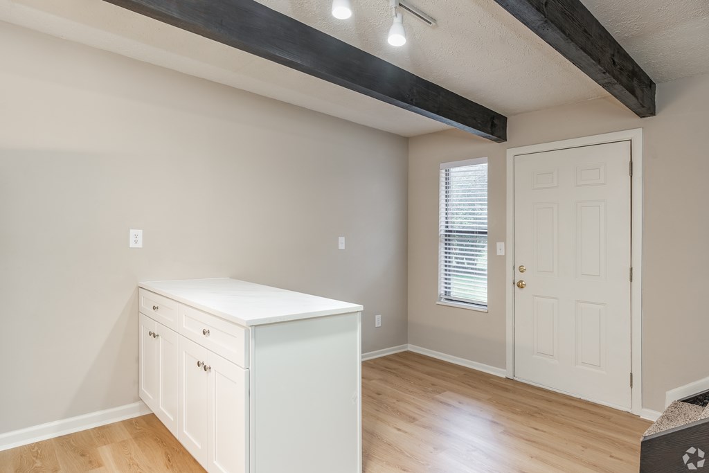 A white cabinet with two drawers is in a room with a white door and a window with blinds.