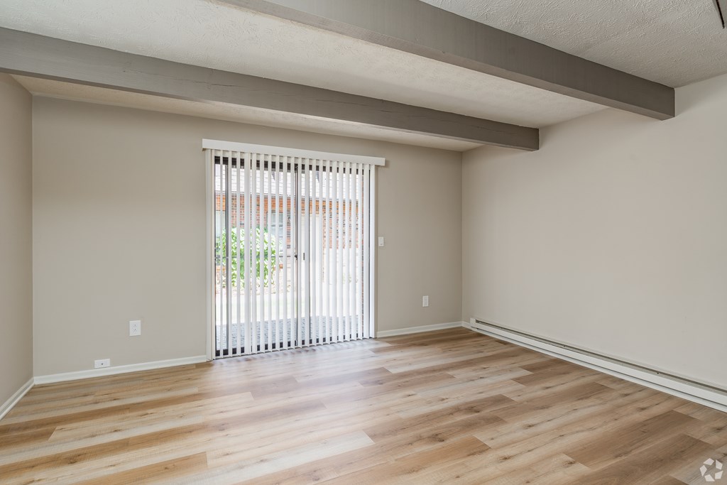 A room with wooden flooring and a sliding glass door.