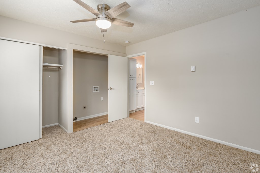 A room with a ceiling fan and carpeted floor.