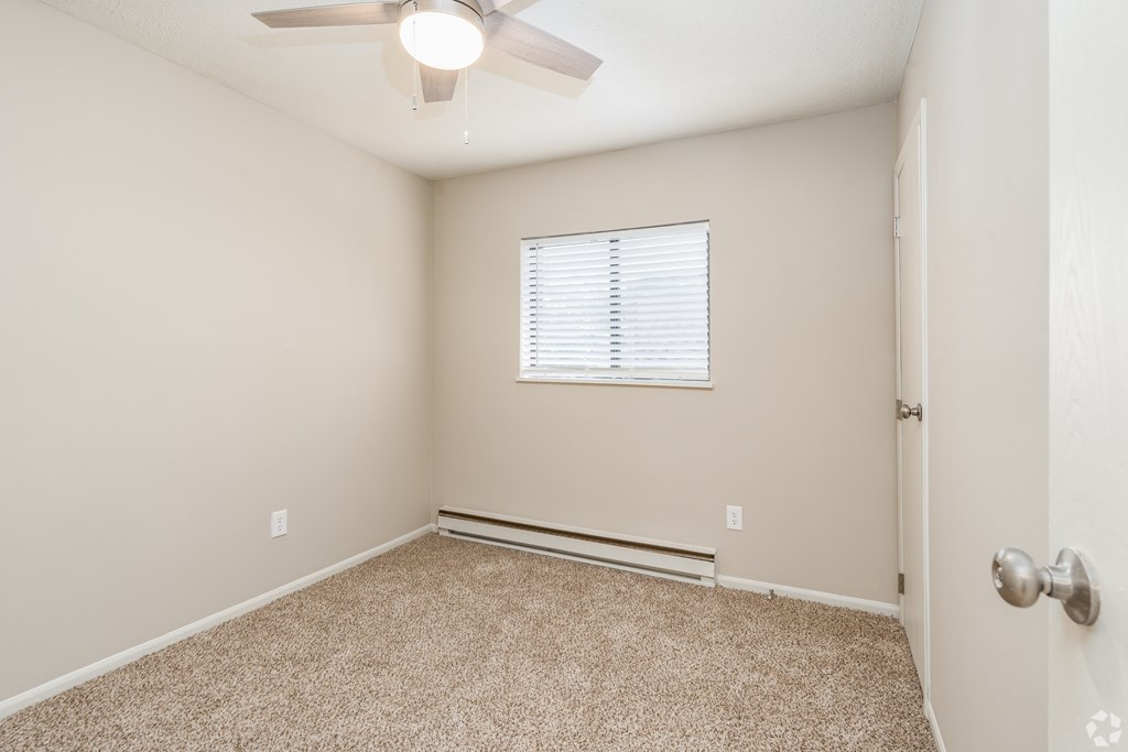 A room with a ceiling fan and a window with blinds.