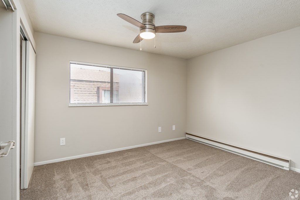 A room with a ceiling fan and a window with blinds.