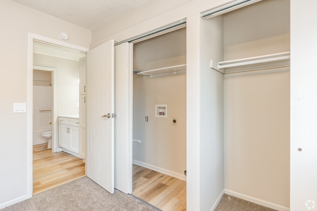 A white door is open to a room with a bed and a small table.