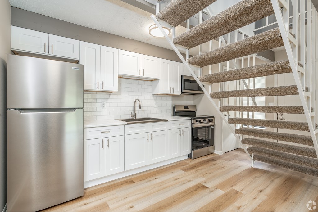 A kitchen with a staircase leading to the upper floor.