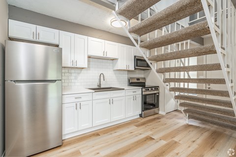 A kitchen with a staircase leading to the upper floor.