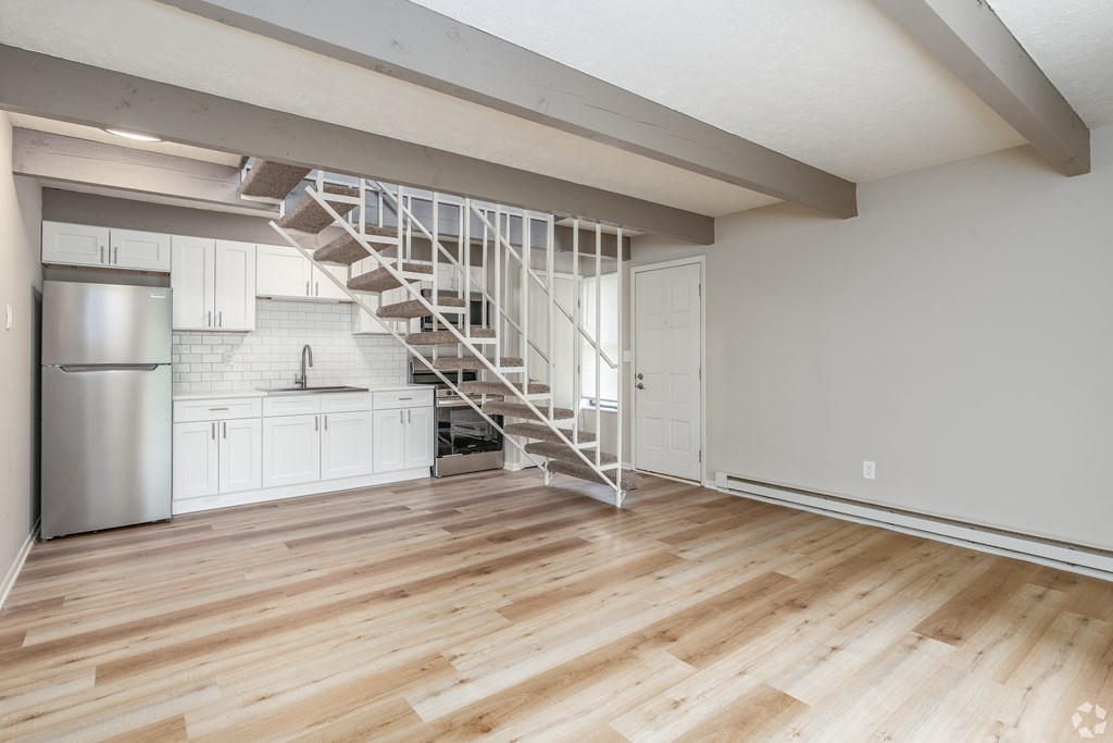 A kitchen with a stainless steel refrigerator and a wooden floor.