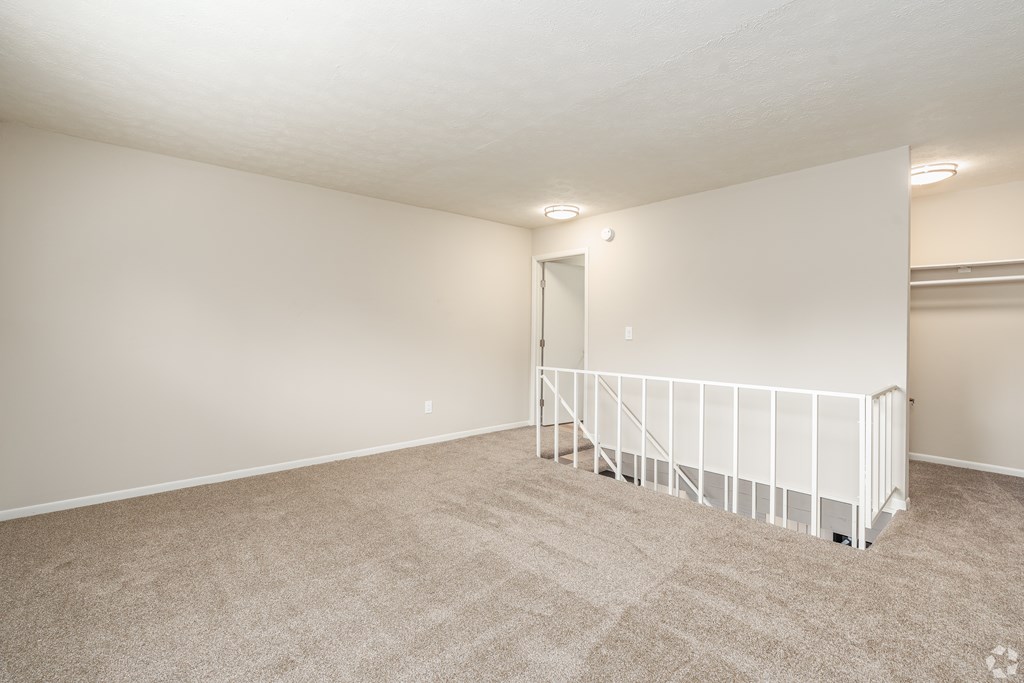 Empty room with carpeted floor and white railings.