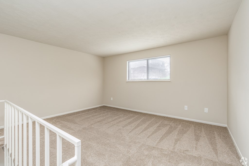 Empty room with a carpeted floor and a window.