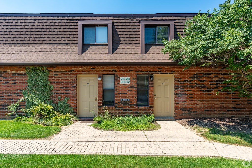 A brick house with a brown roof and a sign on the door.