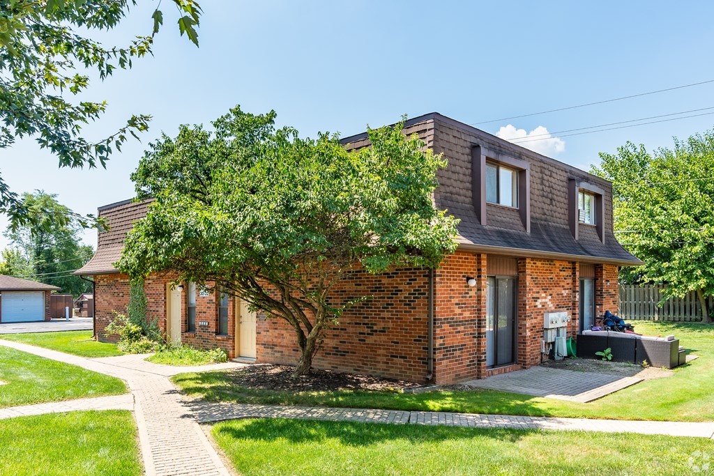 A brick house with a tree in front.