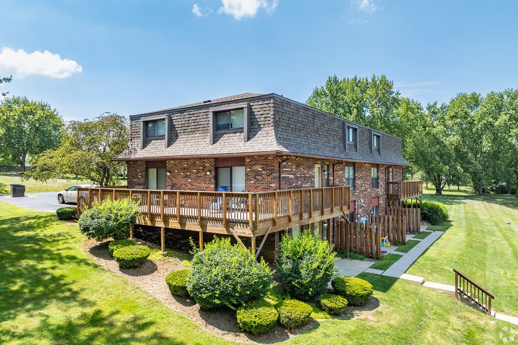 A large house with a wooden deck and a car parked in front.