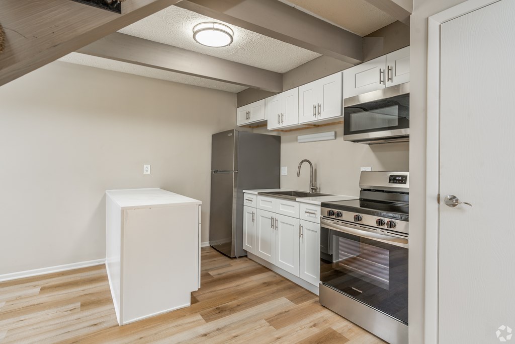 A kitchen with a white fridge and stainless steel appliances.