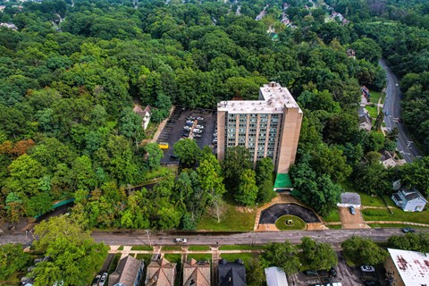 A large building surrounded by trees and a parking lot in front.