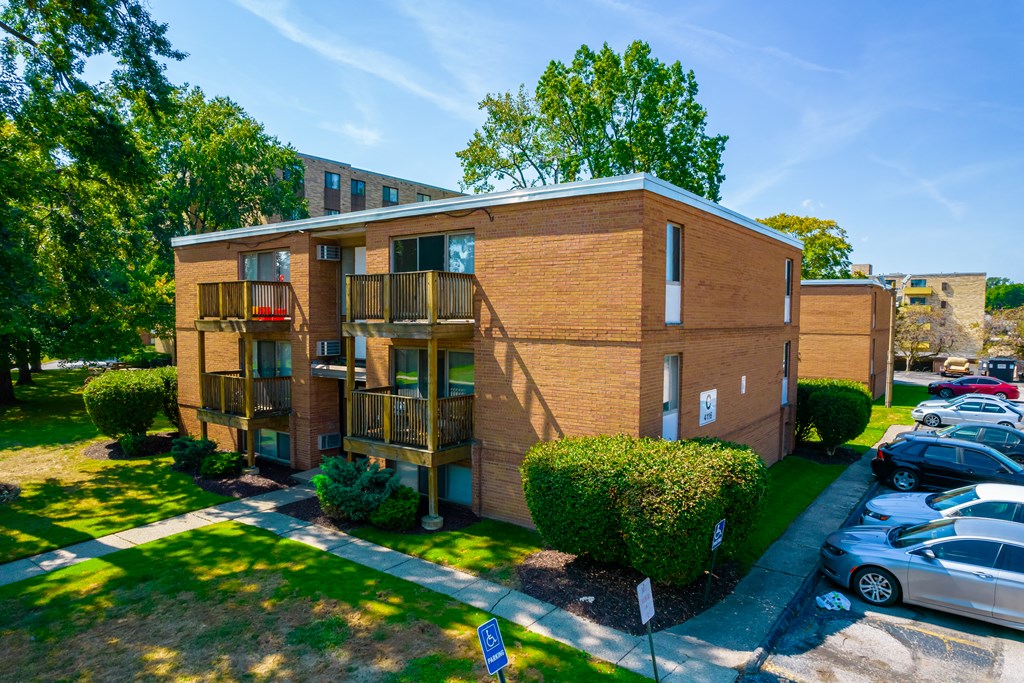 a brick apartment building with balconies and a parking lot
