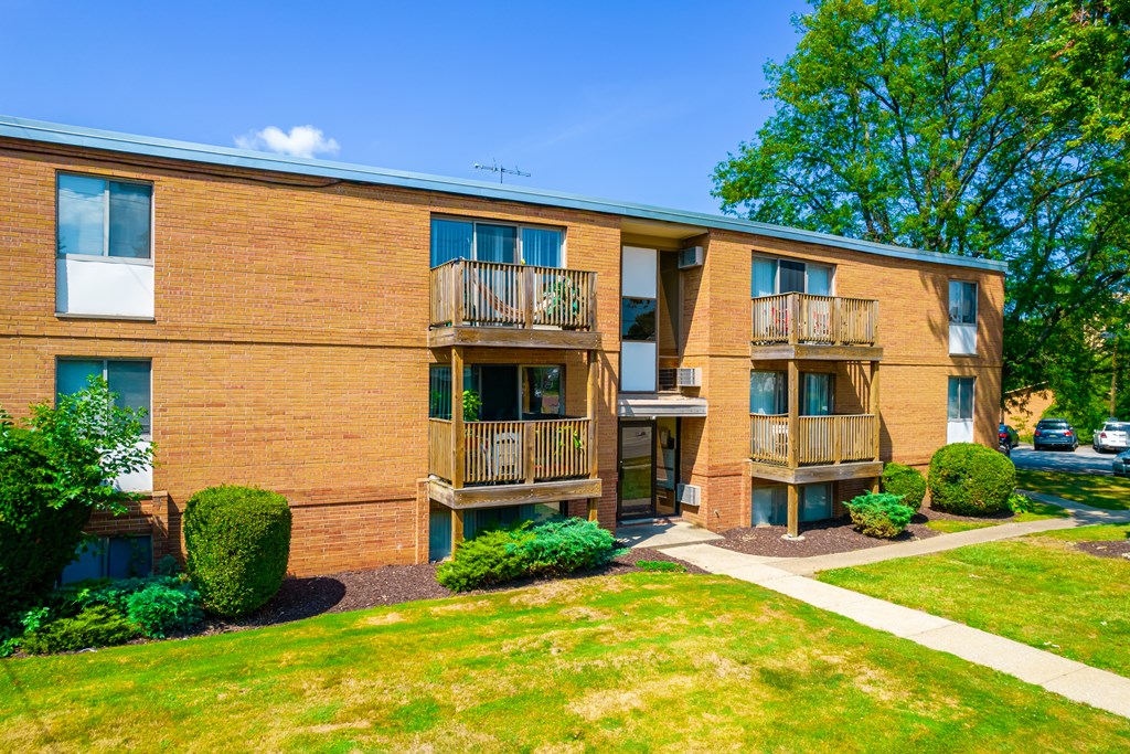 a brick apartment building with balconies and a green lawn
