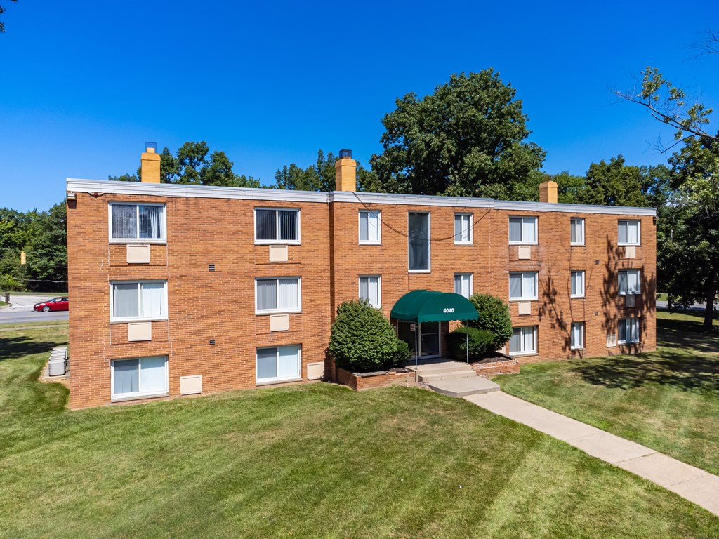a brick apartment building with a green umbrella in front of it