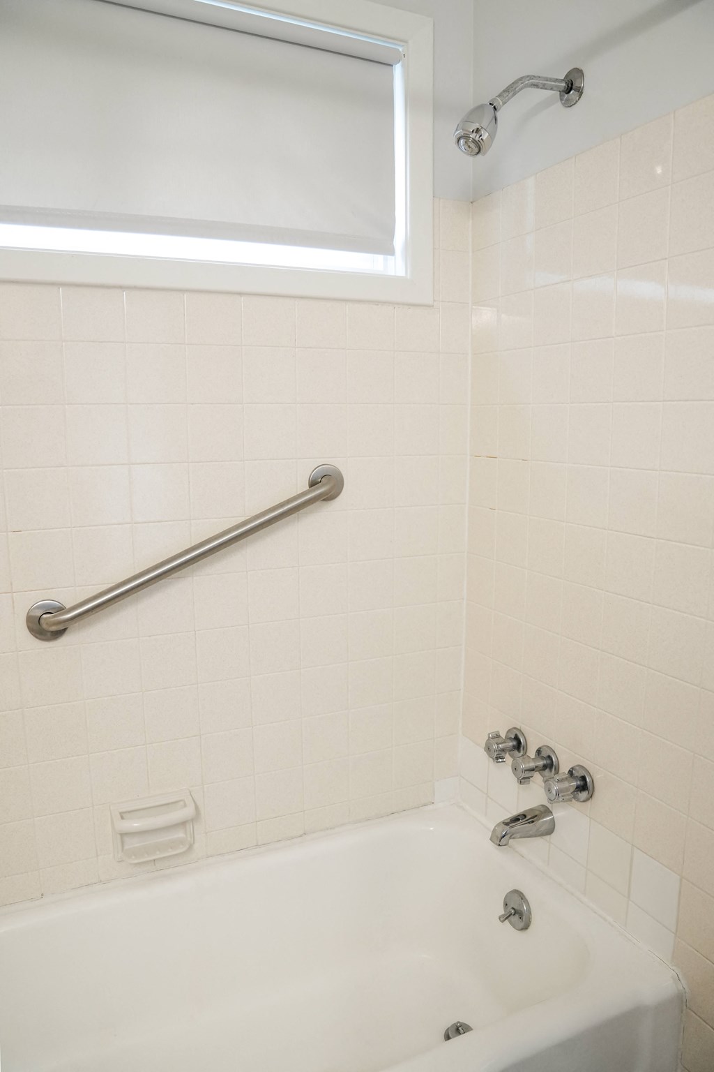 a white bath tub in a bathroom with a rail on the wall