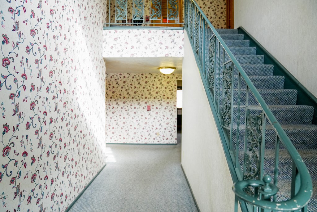 a staircase with a glass railing and a wall with floral wallpaper