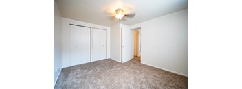 a bedroom with white walls and carpet and a ceiling fan