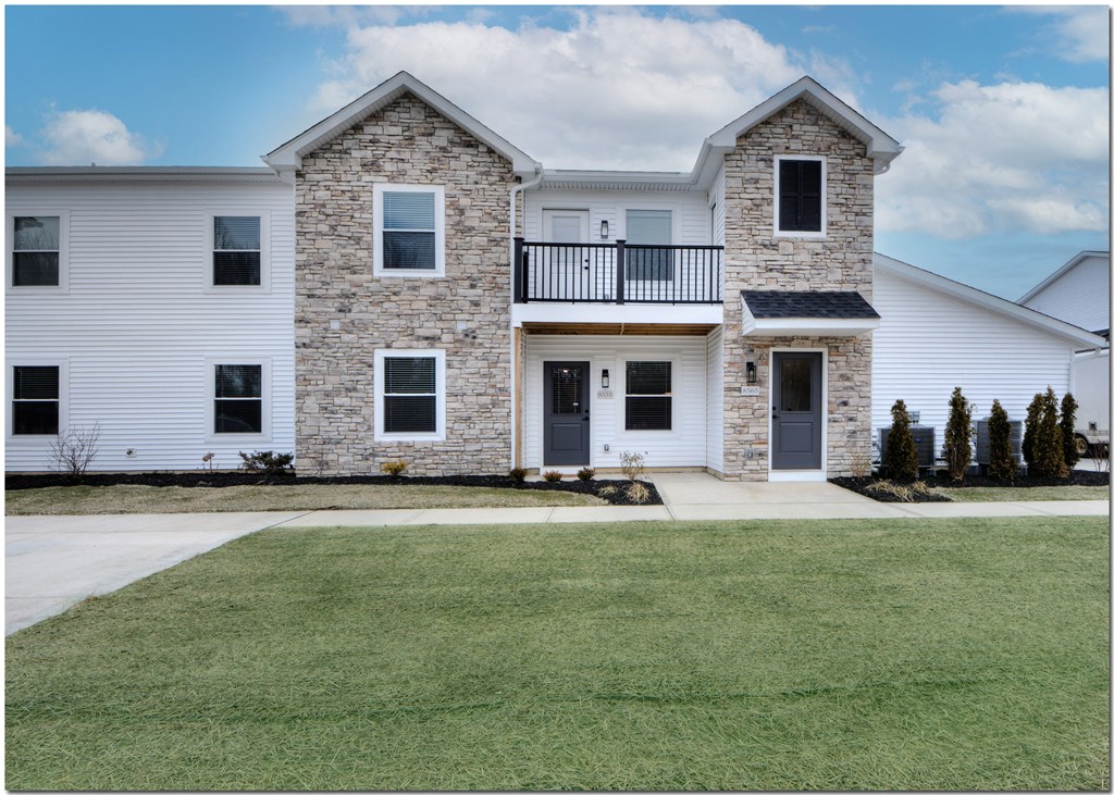 an image of a white house with a yard and a balcony