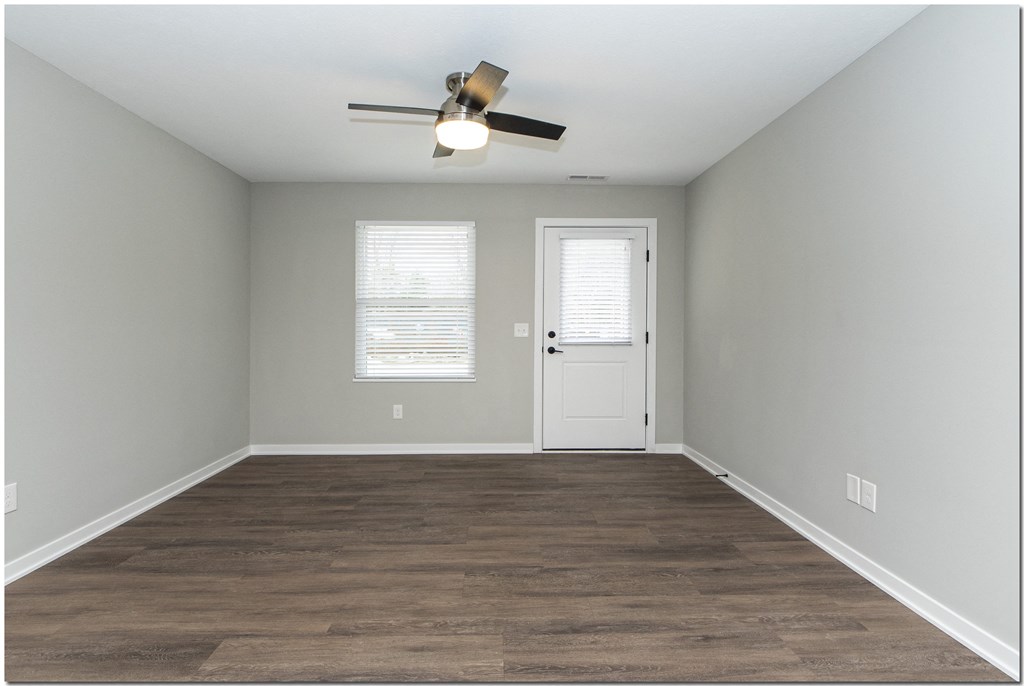 an empty room with a ceiling fan and a door